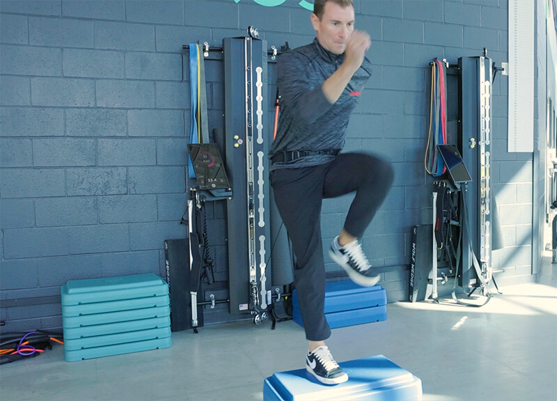 Man performing step ups with belted resistance from a Keiser A400 Performance Trainer