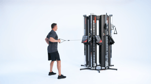 Man performing one arm standing row on Keiser Performance Trainer cable machine