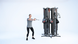 Woman performing a Pallof press on a Keiser performance trainer cable machine