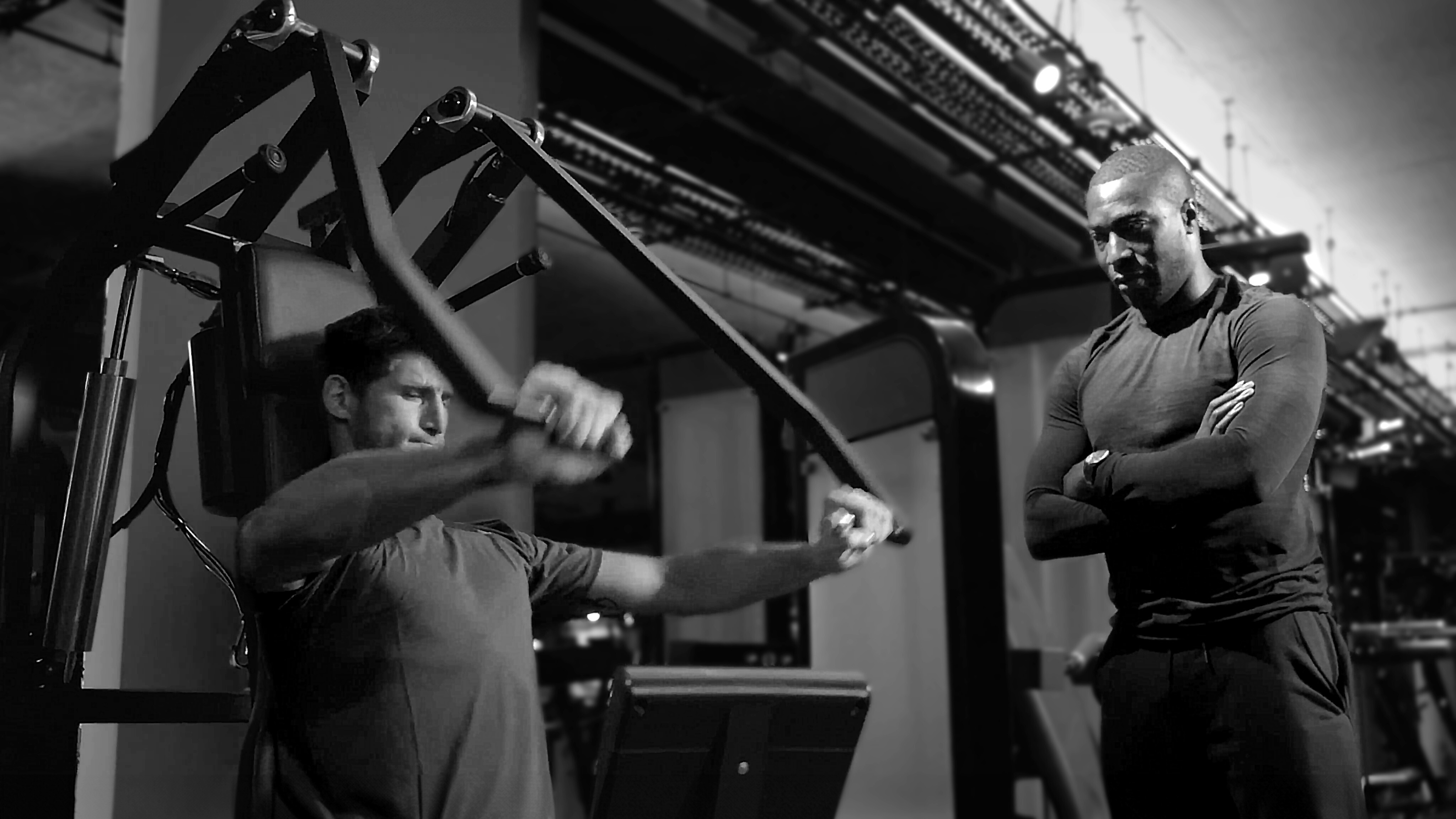 Trainer watching man perform chest press exercise on Keiser machine