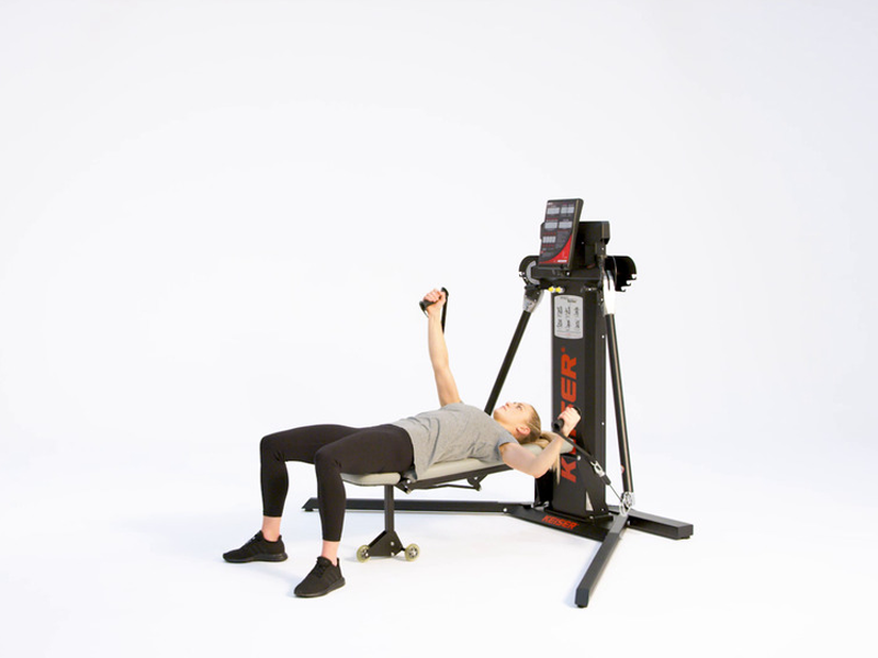 Woman at cable machine conducting alternating bench flies