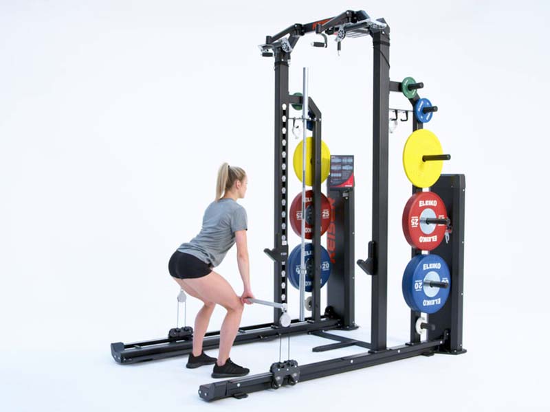 Woman at Rack performing pneumatic resisted high pull to Romanian deadlift
