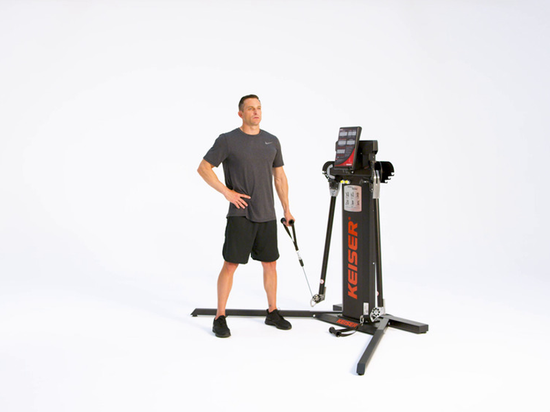 man conducting standing cable bends on Keiser functional trainer
